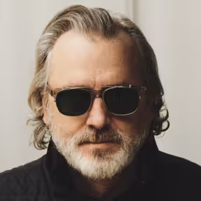 Rob Yeager wearing dark sunglasses and black shirt, shoulder-length hair.